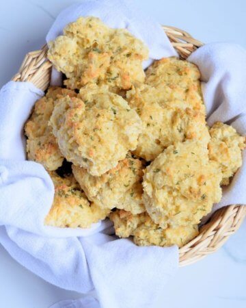 Cheddar Bay biscuits in a wicker basket with a tea towel