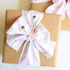 a gift wrapped in brown paper tied with a fabric ribbon