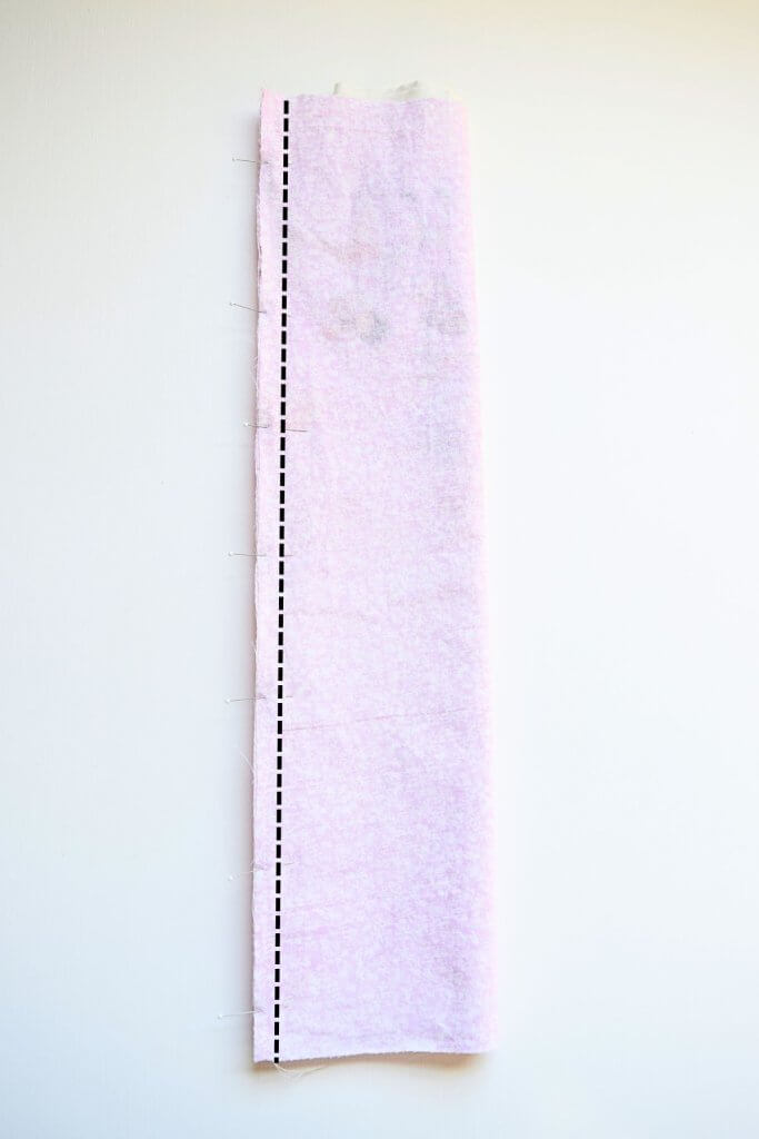a tube of fabric pinned with a dashed black line on it to indicate where to sew